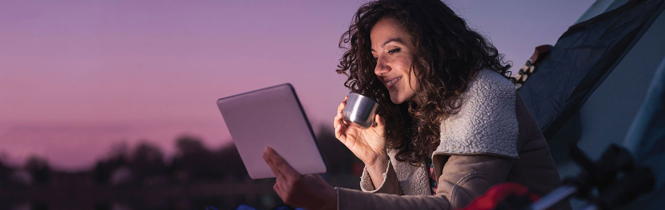 Woman checking her account on a tablet while camping