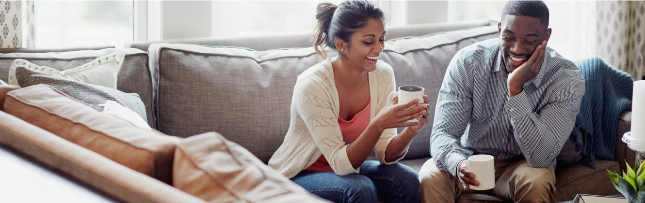 Couple sitting on couch drinking coffee