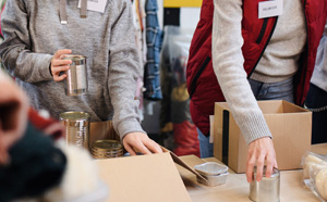 Volunteers putting canned foods into boxes