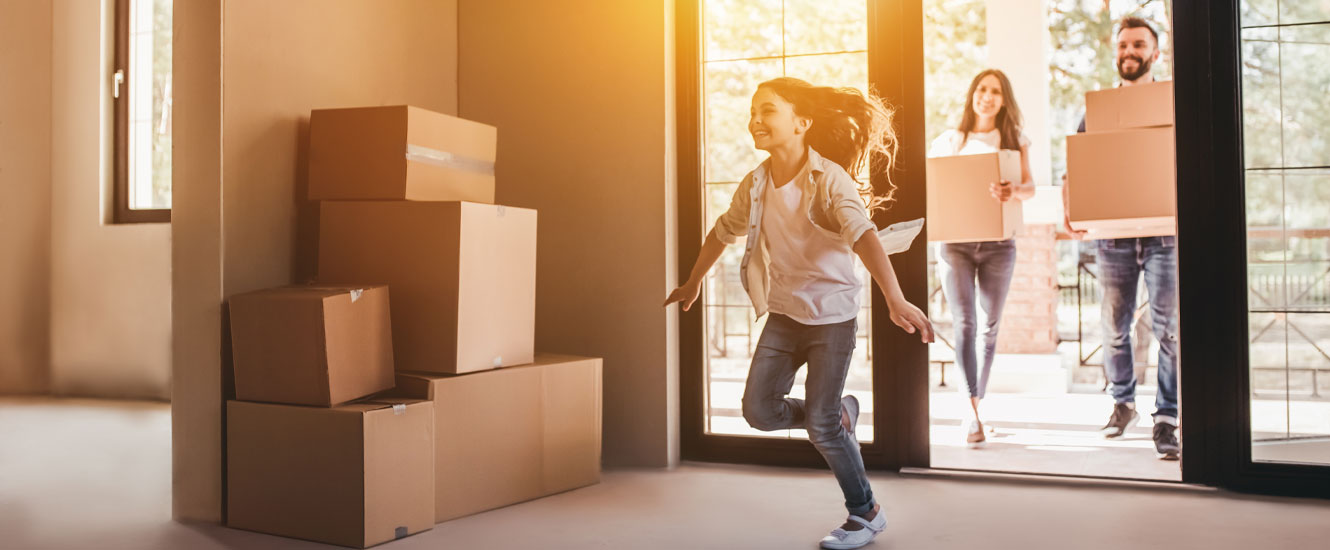 Family carrying moving boxes into new home.