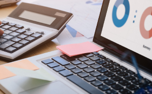 Calculator, laptop and sticky notes on desk