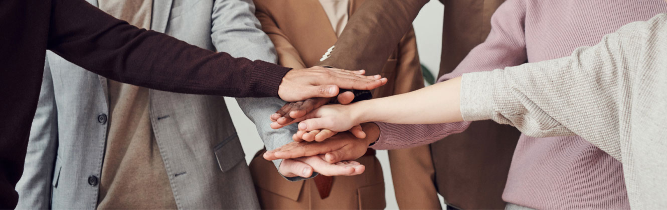 Corporate team huddles with hands in